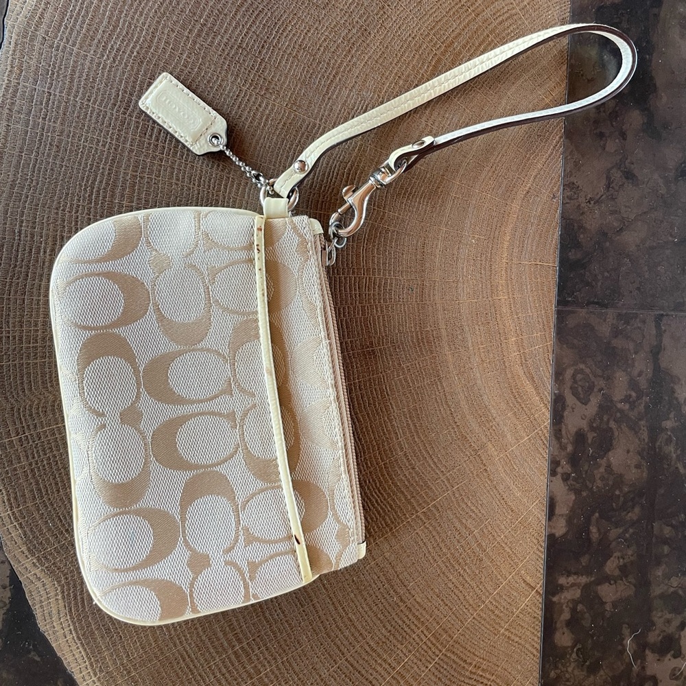 Coach wristlet beige exterior, white handle, and yellow interior.